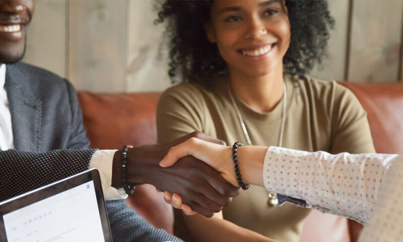 Couple shaking hands with unknown person after making selling their home