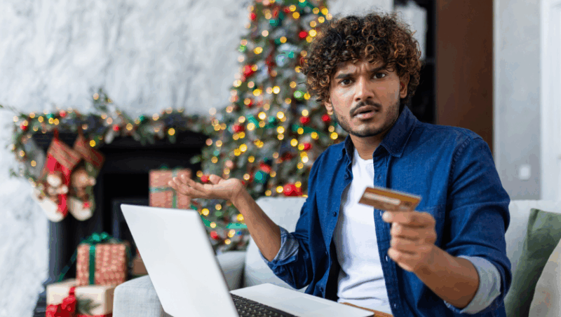 Man holding a credit card with laptop on his lap