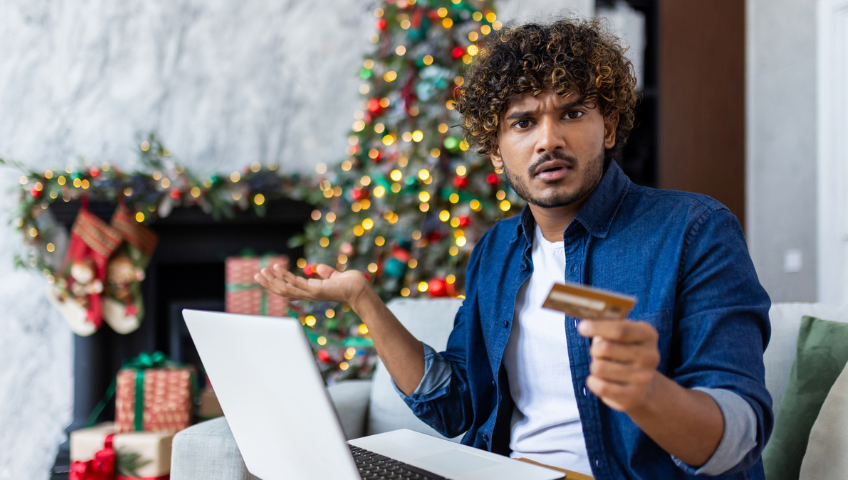 Man holding a credit card with laptop on his lap