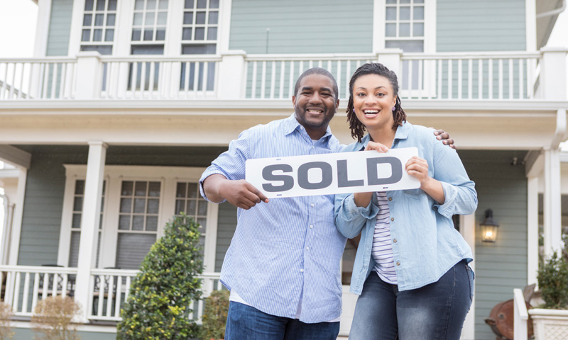 Happy couple holding a sold sign