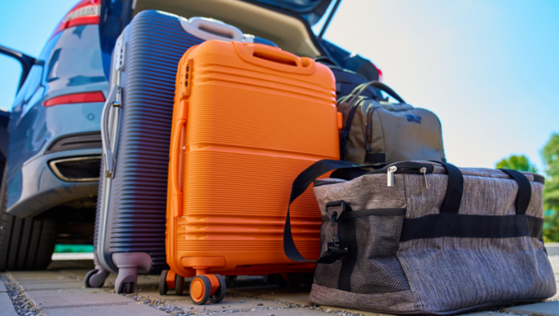 packed suitcases in front of car