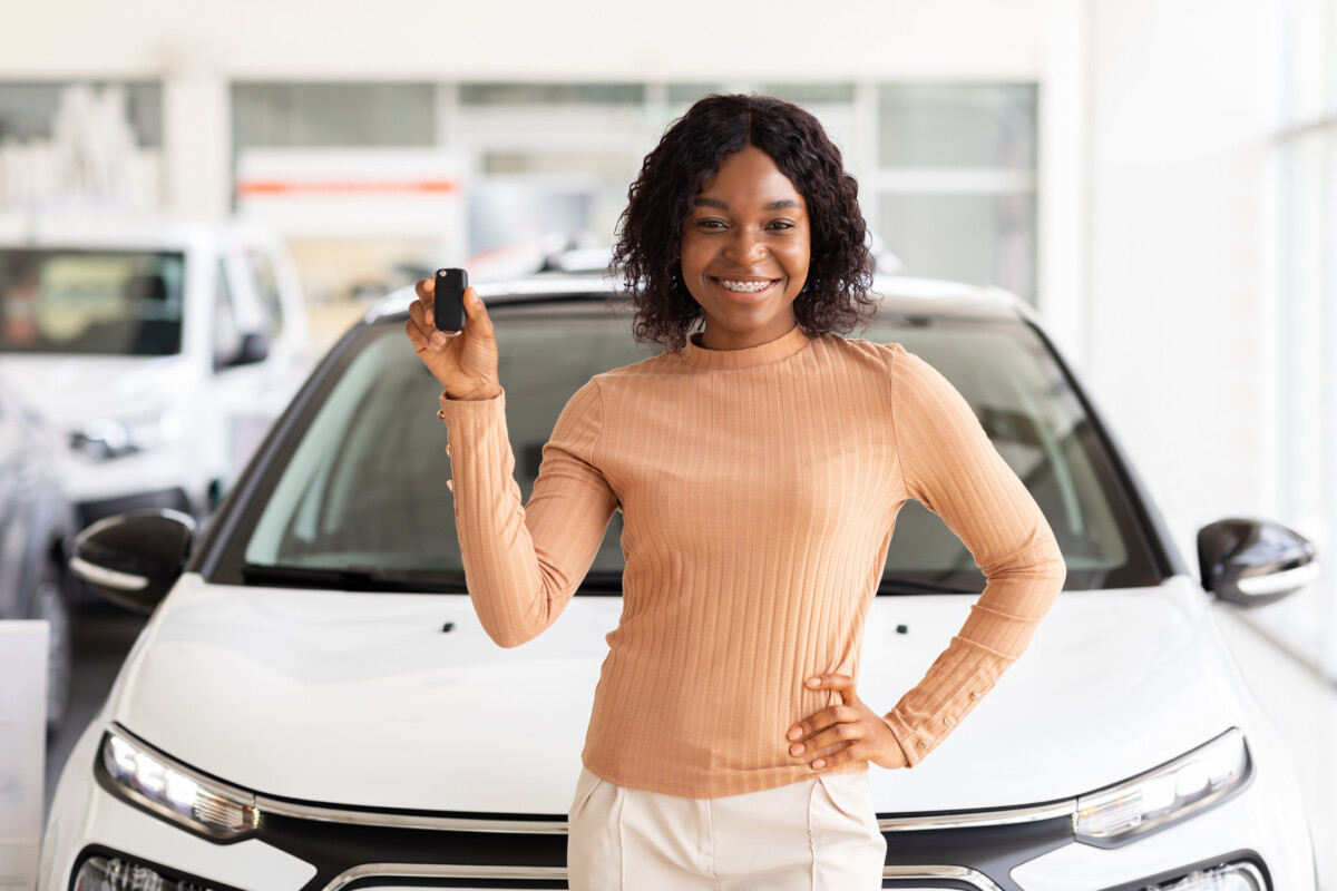 Young adult female holding keys to her new car