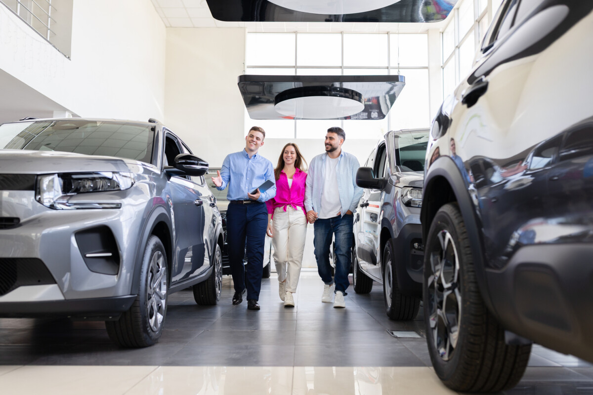 Adult couple walking in dealership with sales man